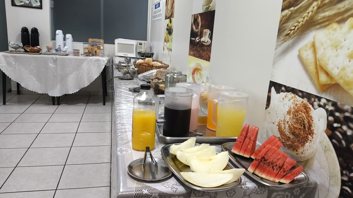 Mesa de café da manhã do Huesca Palace Hotel com pães, frutas e bebidas